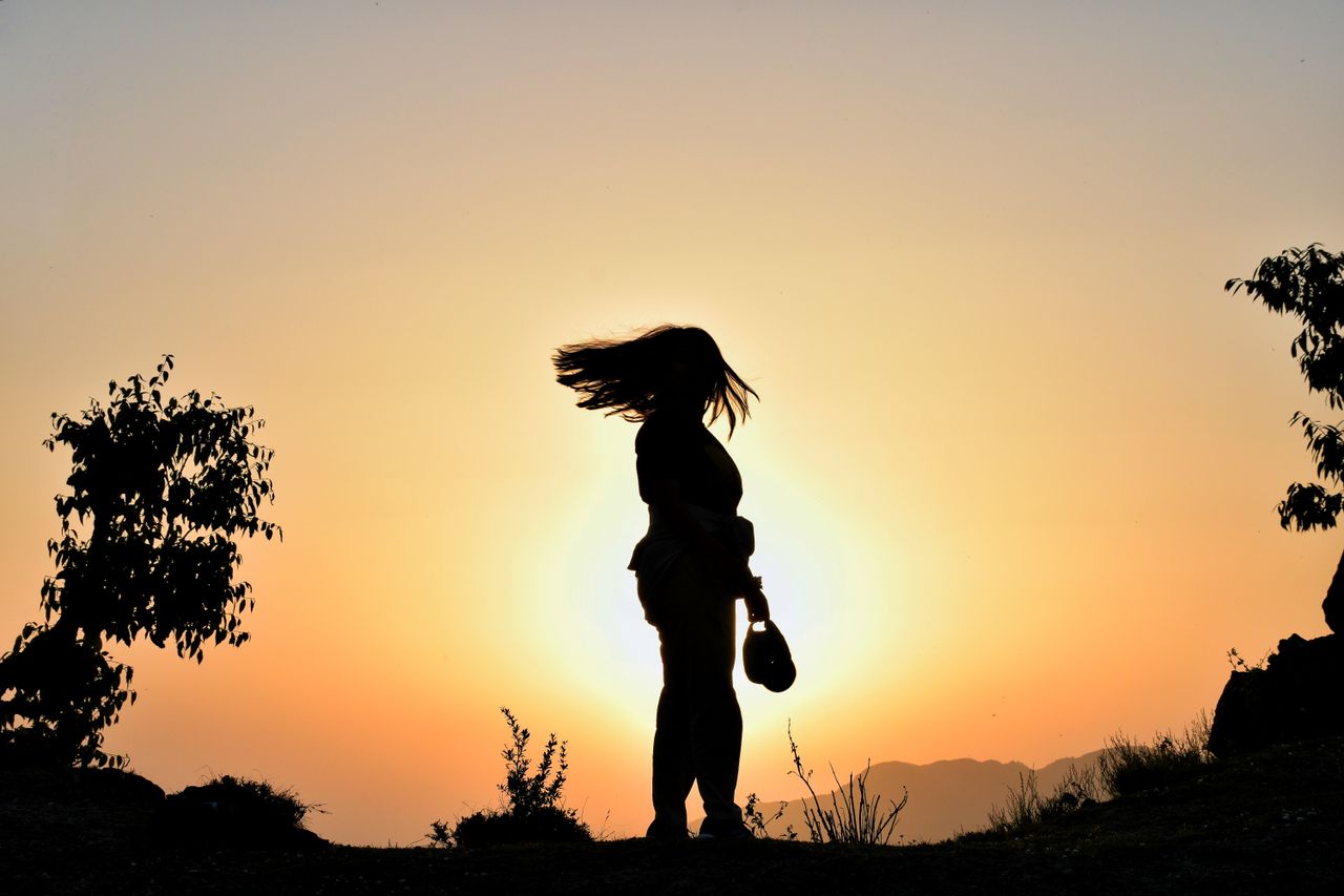 Home Silhouette of a woman at sunset, capturing a serene beauty in the Mussoorie Range.